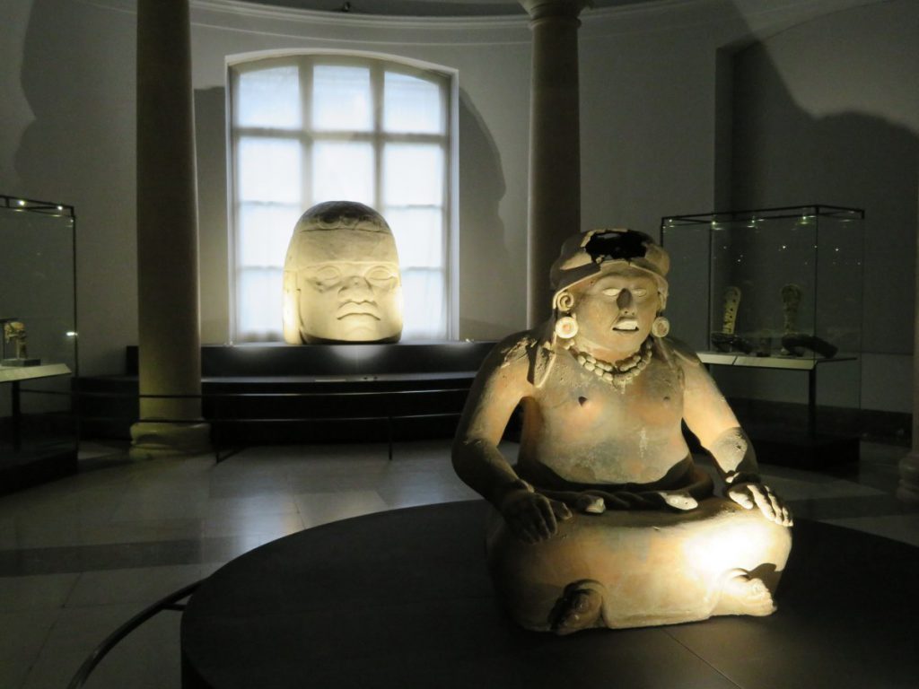 The Aztec fertility goddess Cihuacoatl, in front of an Olmec colossal stone head.